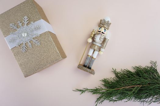 On the table there is a wooden Nutcracker toy, a gift in a gold package and a coniferous branch. High quality photo