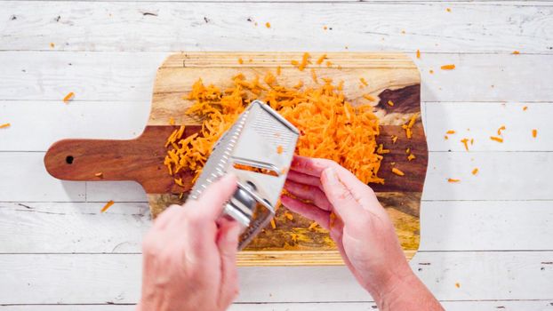 Flat lay. Grated organic orange carrots on a wood cutting board.