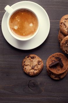 Homemade chocolate chip cookies and a cup of coffee on dark old wooden table. Sweet dessert.