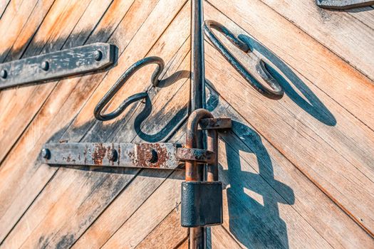 Vintage wooden gate with hanging rusty padlock closeup