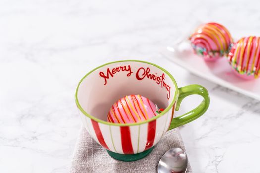 Preparing Christmas hot chocolate bombs with hot milk in a Christmas mug.