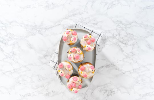 Freshly baked mini Easter bread kulich with lemon glaze, decorated with sprinkles and meringue bird-shaped cookies.