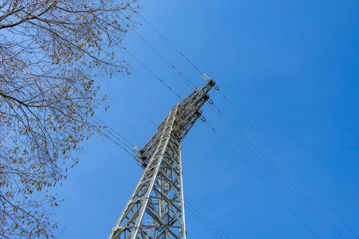 View from below of a power transmission tower against the sky. City infrastructure