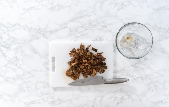Flat lay. Cutting dehydrated wild mushrooms on a white cutting board.