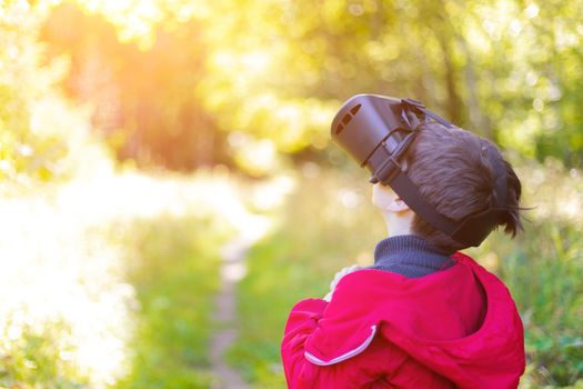 A boy in virtual reality glasses on the street . Modern children . 3D glasses. Modern technologies. Virtual games