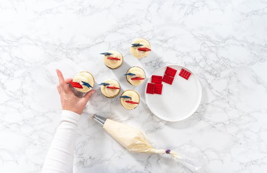 Flat lay. Decorating lemon cupcakes with patriotic blue chocolate star and red mini chocolate.