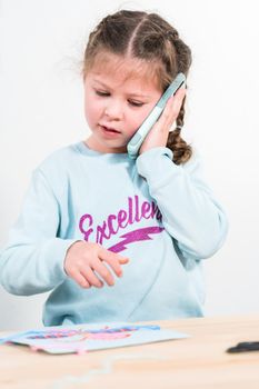 Little girl talking on the phone with her school friends.