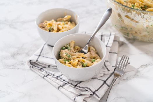 Serving macaroni salad with chicken in white ceramic bowls.