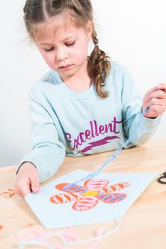 Little girl learning how to sew with sewing craft kit for kids.