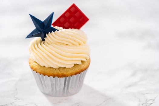 Lemon cupcakes with lemon buttercream frosting, and decorated with patriotic blue chocolate star and red mini chocolate.