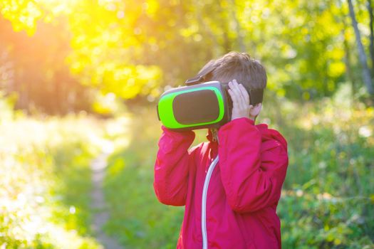 A boy in virtual reality glasses on the street . Modern children . 3D glasses. Modern technologies. Virtual games