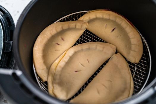 Frying sweet cherry empanadas in the air fryer.