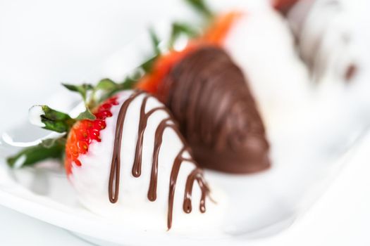 White and dark chocolate dipped strawberries on a white cake stand.