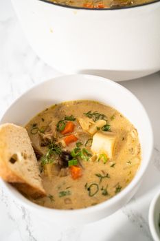 Serving creamy wild mushroom soup made out of dehydrated wild mushrooms in white bowls with sourdough bread.