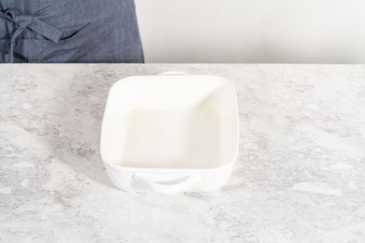 Greasing white casserole dish to bake bread pudding.