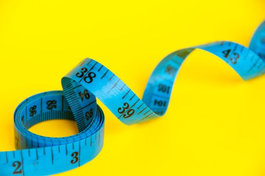Blue measuring tapes on yellow cover background with customizable space for text or ideas. Copy space and weight loss concept.
