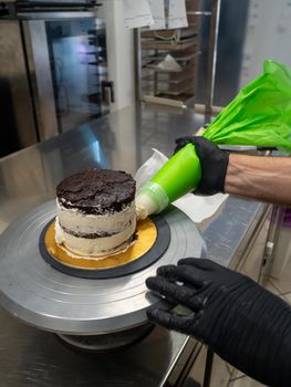 decorator applying buttercream to frosted cake with bag full of cream