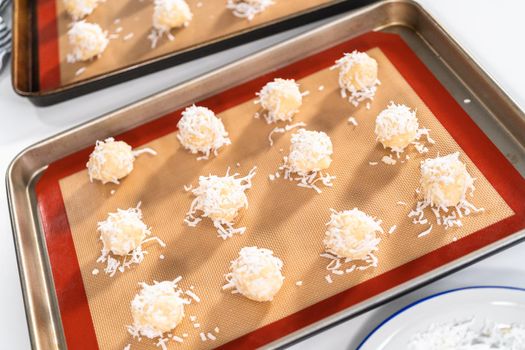 Unbaked dough scoops on the baking sheet to bake coconut cookies.