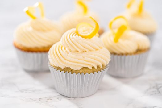 Lemon cupcakes with lemon buttercream frosting, and decorated with lemon swist.