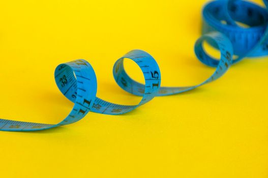 Blue measuring tapes on yellow cover background with customizable space for text or ideas. Copy space and weight loss concept.