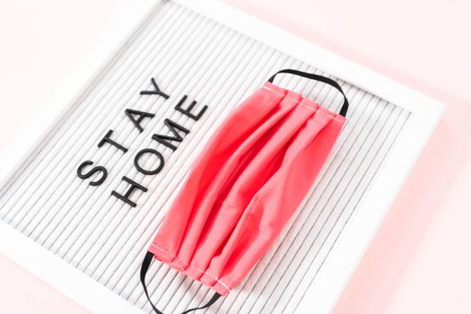 STAY HOME sign on message board with a homemade face mask.