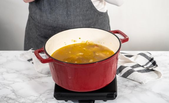 Cooking chicken noodle soup with kluski noodles in an enameled dutch oven.
