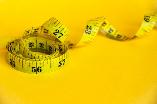 Measuring tapes on yellow cover background with customizable space for text or ideas. Copy space and weight loss concept.