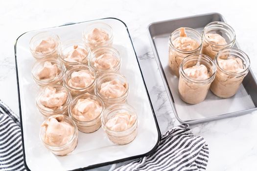 Scooping mixture into the small glass jars to make homemade chocolate ice cream.