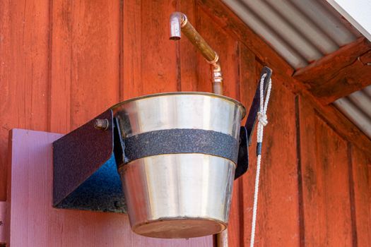 Image of Wooden bucket on a rope with cold water in sauna, finish, cold shower of pails