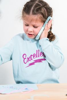 Little girl talking on the phone with her school friends.