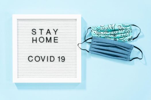 STAY HOME and COVID-19 sign on message board with a homemade face mask.