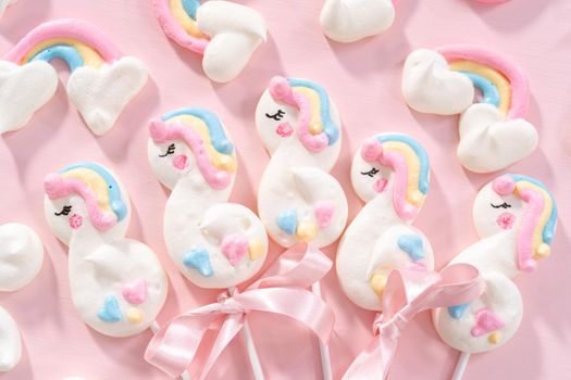 Gourmet unicorn theme meringue pops on a pink background.