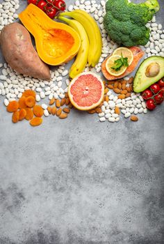 Vegetables, fruit and foods containing potassium, stone background, top view, space for text. Natural sources of potassium, vitamins and micronutrients, healthy balanced diet, avitaminosis prevention