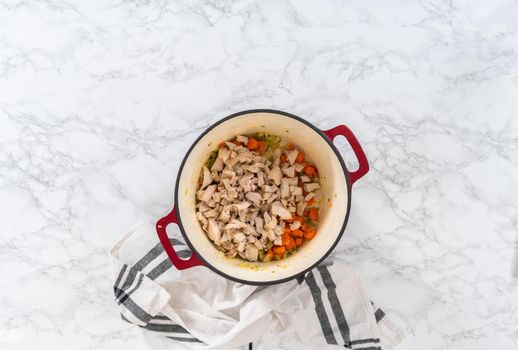 Flat lay. Cooking chicken noodle soup with kluski noodles in an enameled dutch oven.