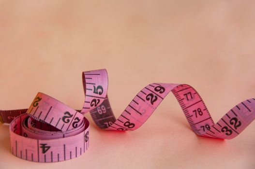 Red measuring tapes on pink cover background with customizable space for text or ideas. Copy space and weight loss concept.