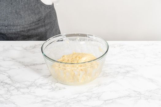 Mixing ingredients with a hand whisk in a glass mixing bowl to bake lemon cupcakes.