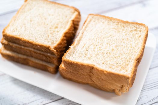 Stack of texas toast on a white plate, ready to prepare french toast.