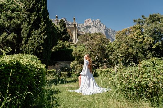 a beautiful woman with long brown hair stay along a path along beautiful bushes in the park