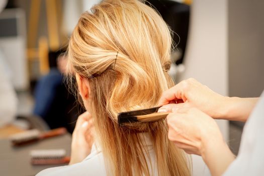 A hairdresser is combing female hairstyling in a hairdressing beauty salon