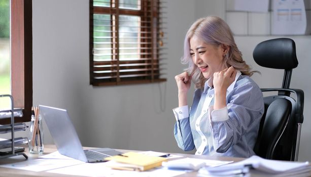 Portrait of happy young business asian woman celebrating success with arms up. positive expression, success in business concept..