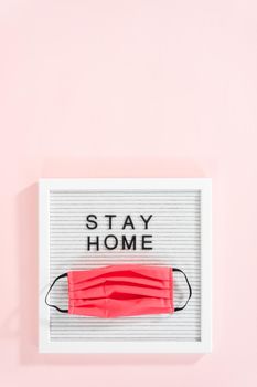 STAY HOME sign on message board with a homemade face mask.