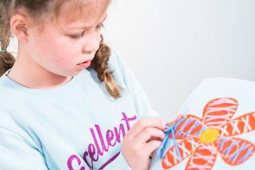 Little girl learning how to sew with sewing craft kit for kids.