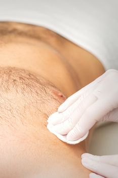 Young caucasian man receiving hair removal from his chest in a beauty salon, depilation men's torso