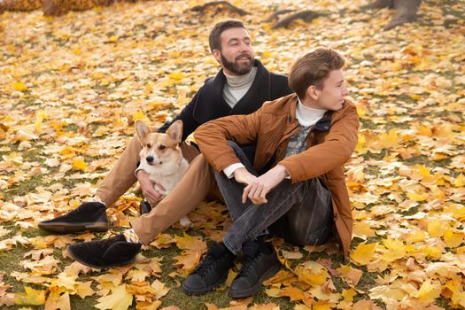 Father and son with a pet on a walk in the autumn park.