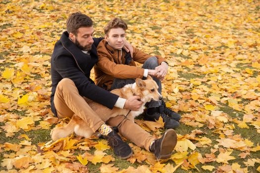 Father and son with a pet on a walk in the autumn park.