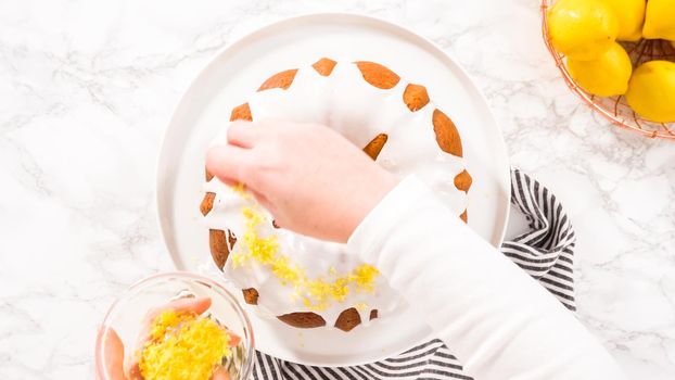 Flat lay. Step by step. Garnishing lemon bundt cake with lemon zest on top of the white glaze.