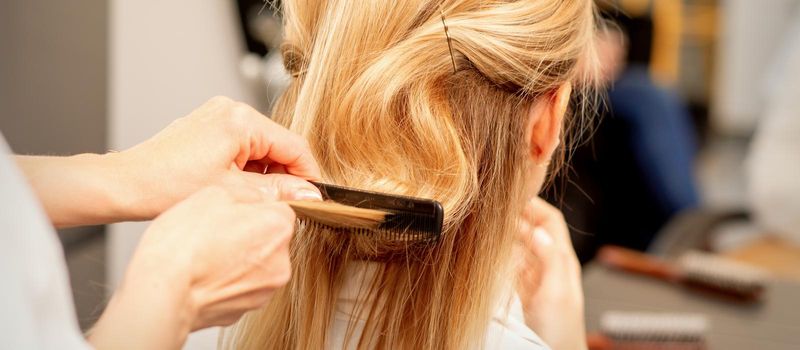 A hairdresser is combing female hairstyling in a hairdressing beauty salon