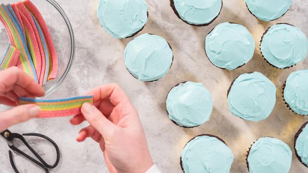 Flat lay. Step by step. Decorating chocolate cupcakes with buttercream frosting and rainbow candy.