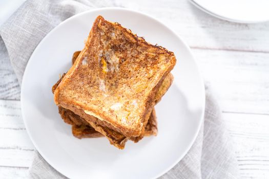 Stack of freshly baked french toast on a white plate.