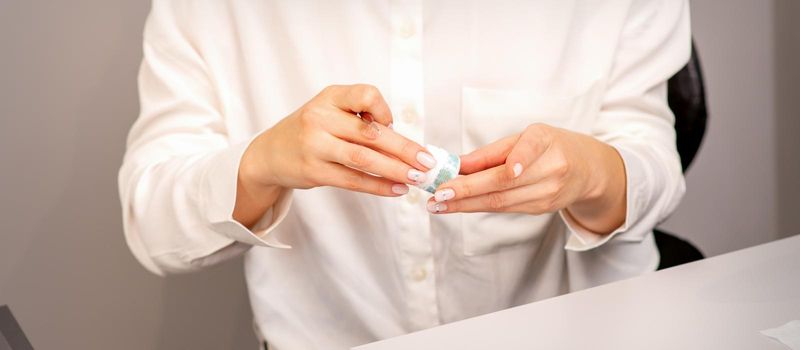 Manicure master's hands with beautiful manicure holding case box with nail sequins in nail salon